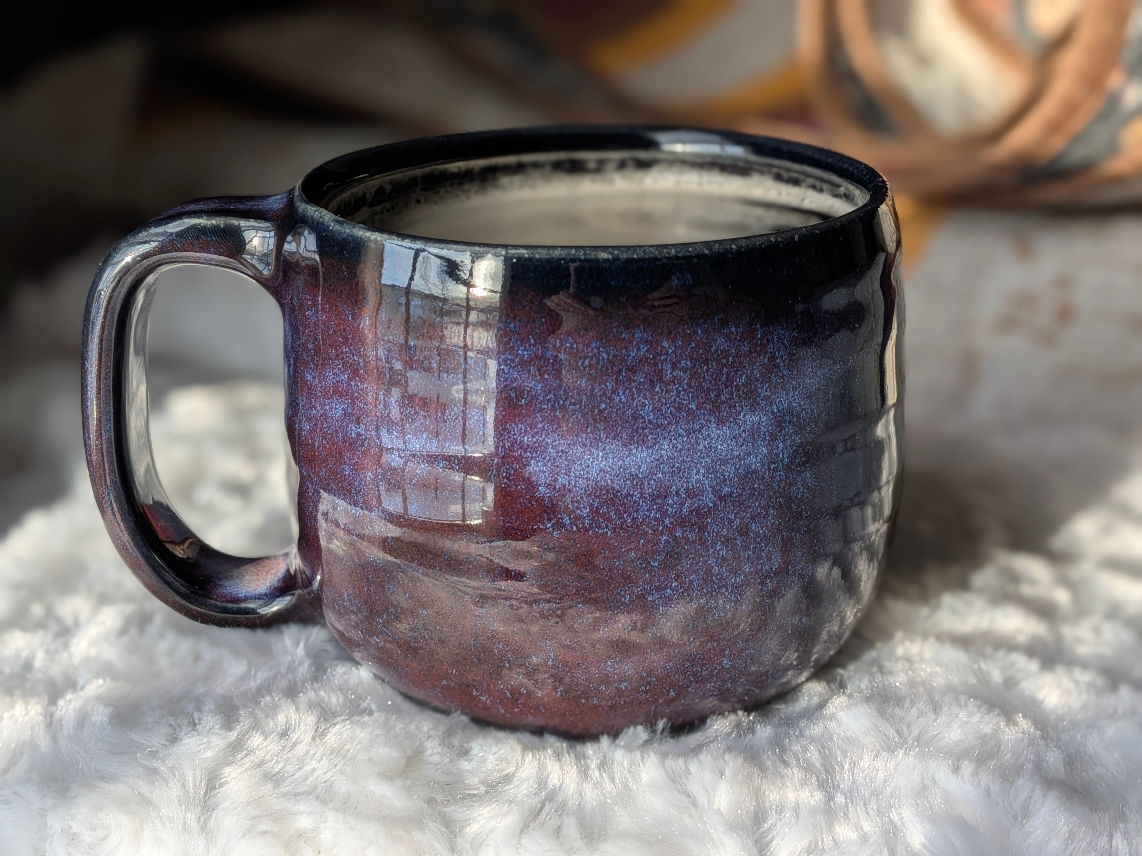 Ceramic mug with a purple glaze on a textured surface